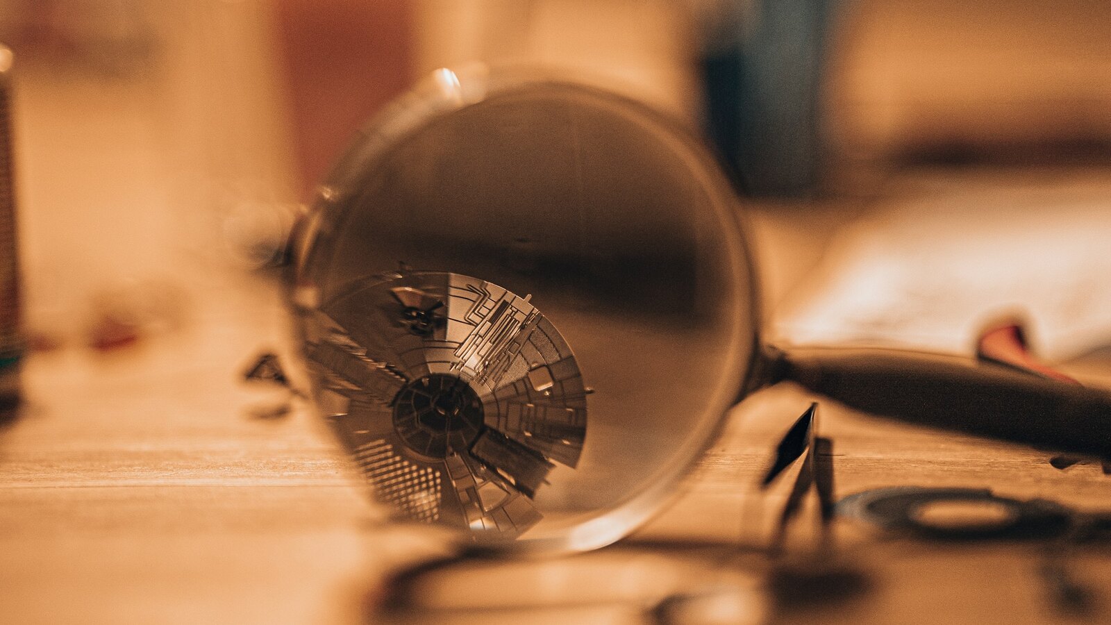 A magnifying glass over old letters on a dark desk